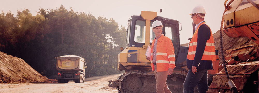 Workers at an outdoor work site on a road with machines