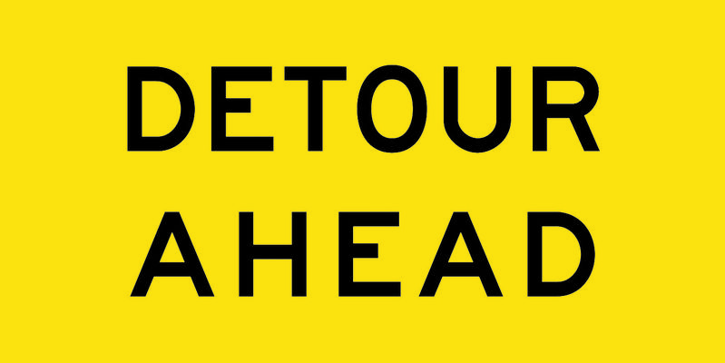 A yellow and black Detour Ahead Sign