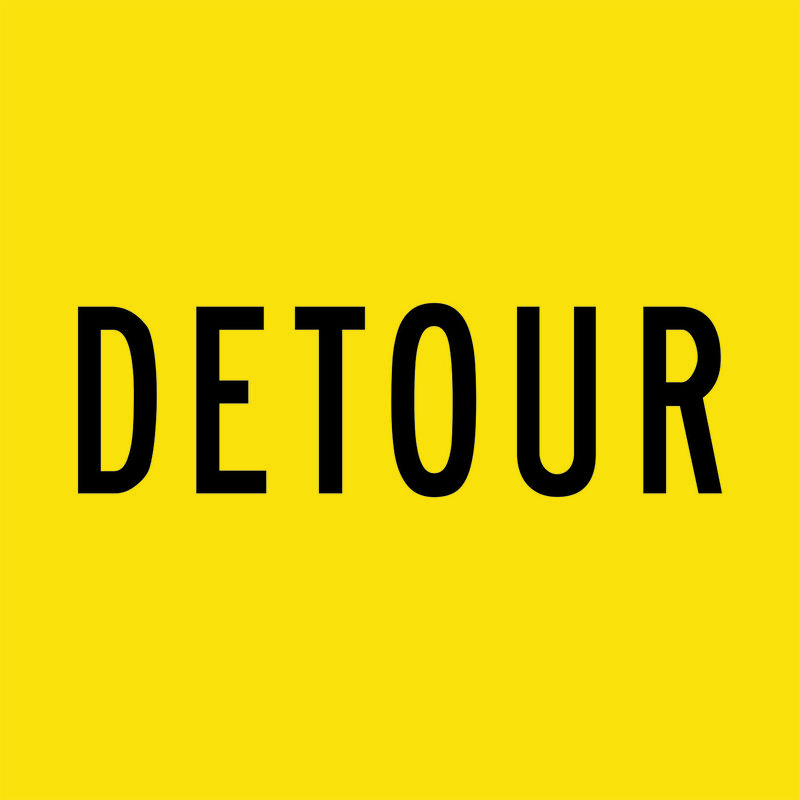 A yellow and black Detour Sign