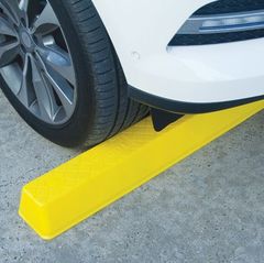 A yellow Plastic Wheel Stop under the front of a white car